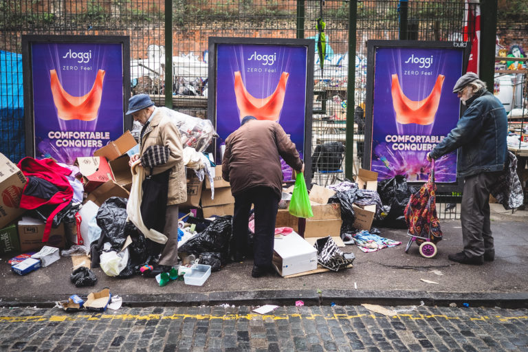 three men sort through jumble at a market in brick lane london, photographed by Simon Hawkins Pictures